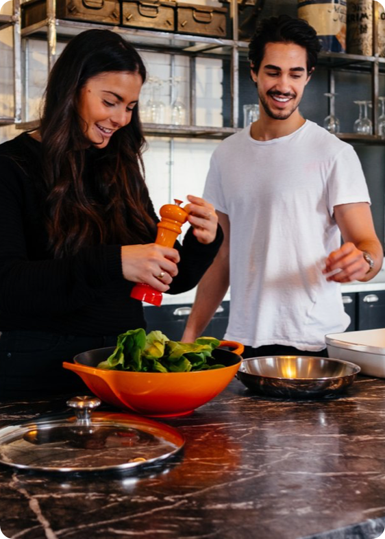 Couple cooking together and laughing, practicing eating better